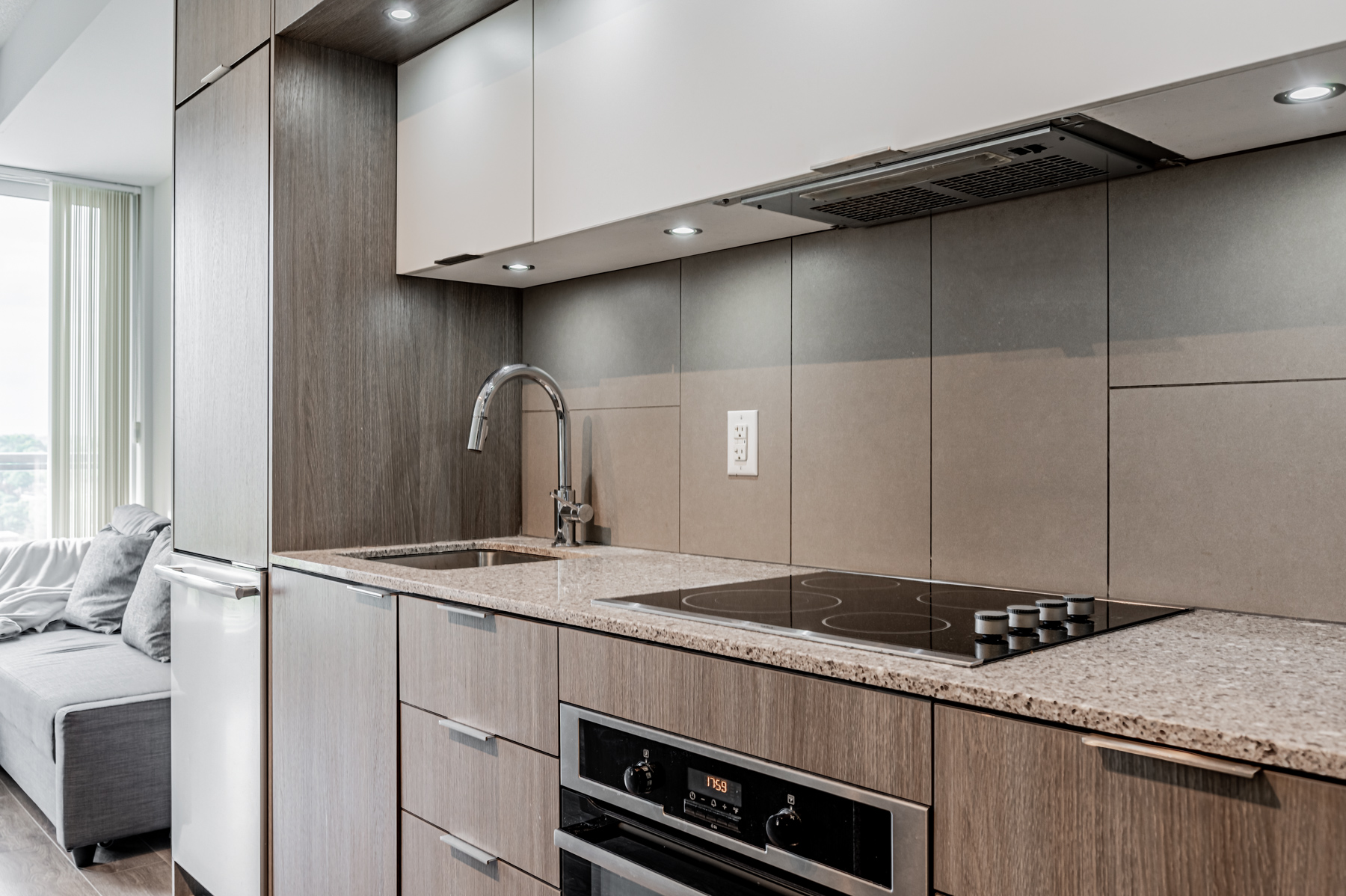 Beautiful condo kitchen with quartz countertops, large tile back-splash and wooden cabinets.