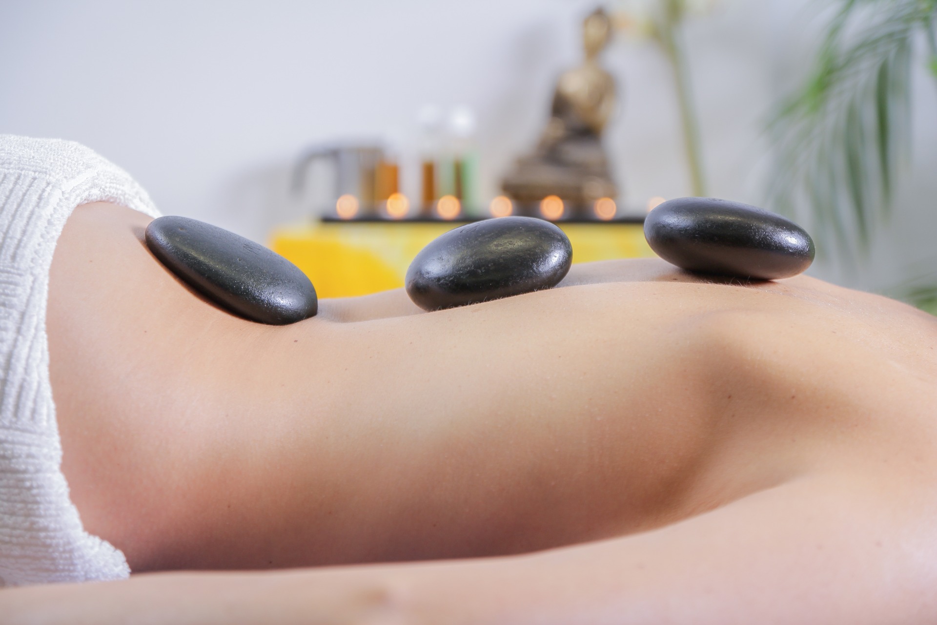 Image of hot stone therapy showing woman's back with 3 dark, circular stones