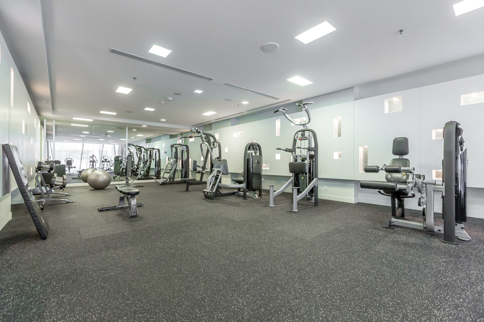 Photo of condo's fitness centre. Picture shows so many pieces of equipment. The space is rather large. 