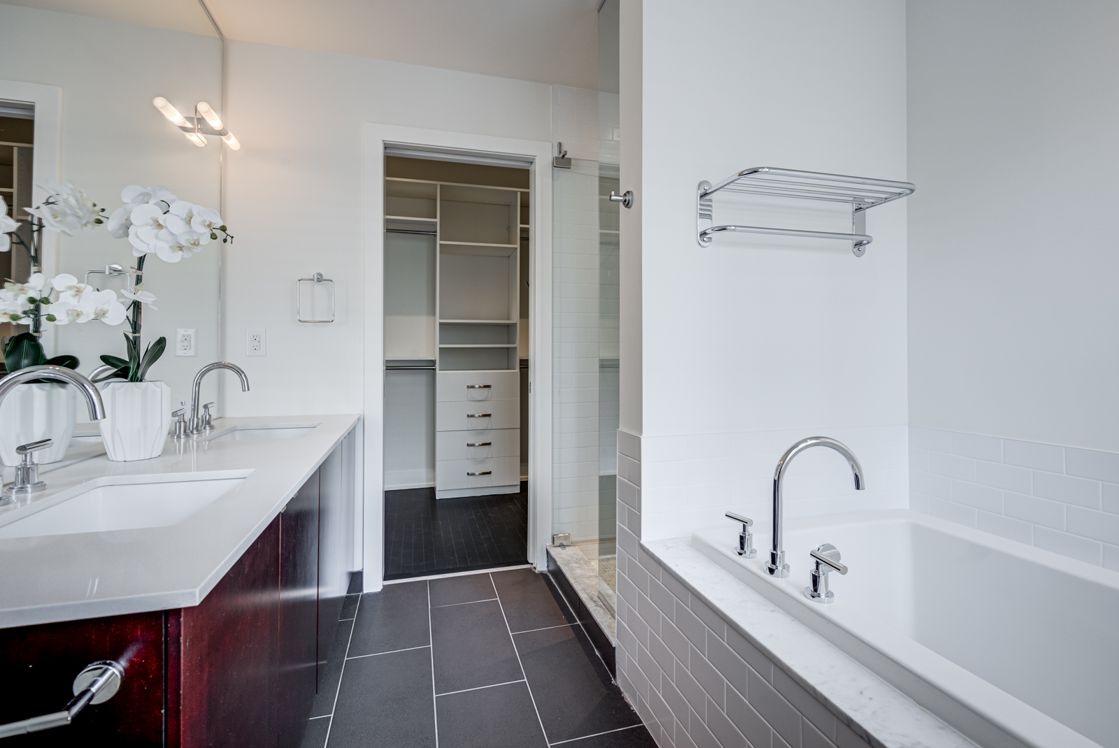 master bath with his and her sinks, soaker tub and black floor tiles.