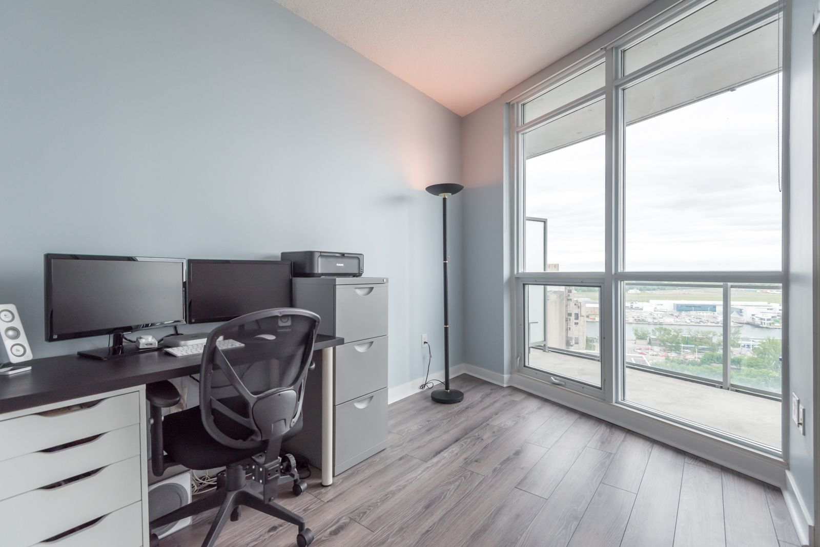 Image of second bedroom and another view of balcony. It also shows a desk and chair and laminate floors.