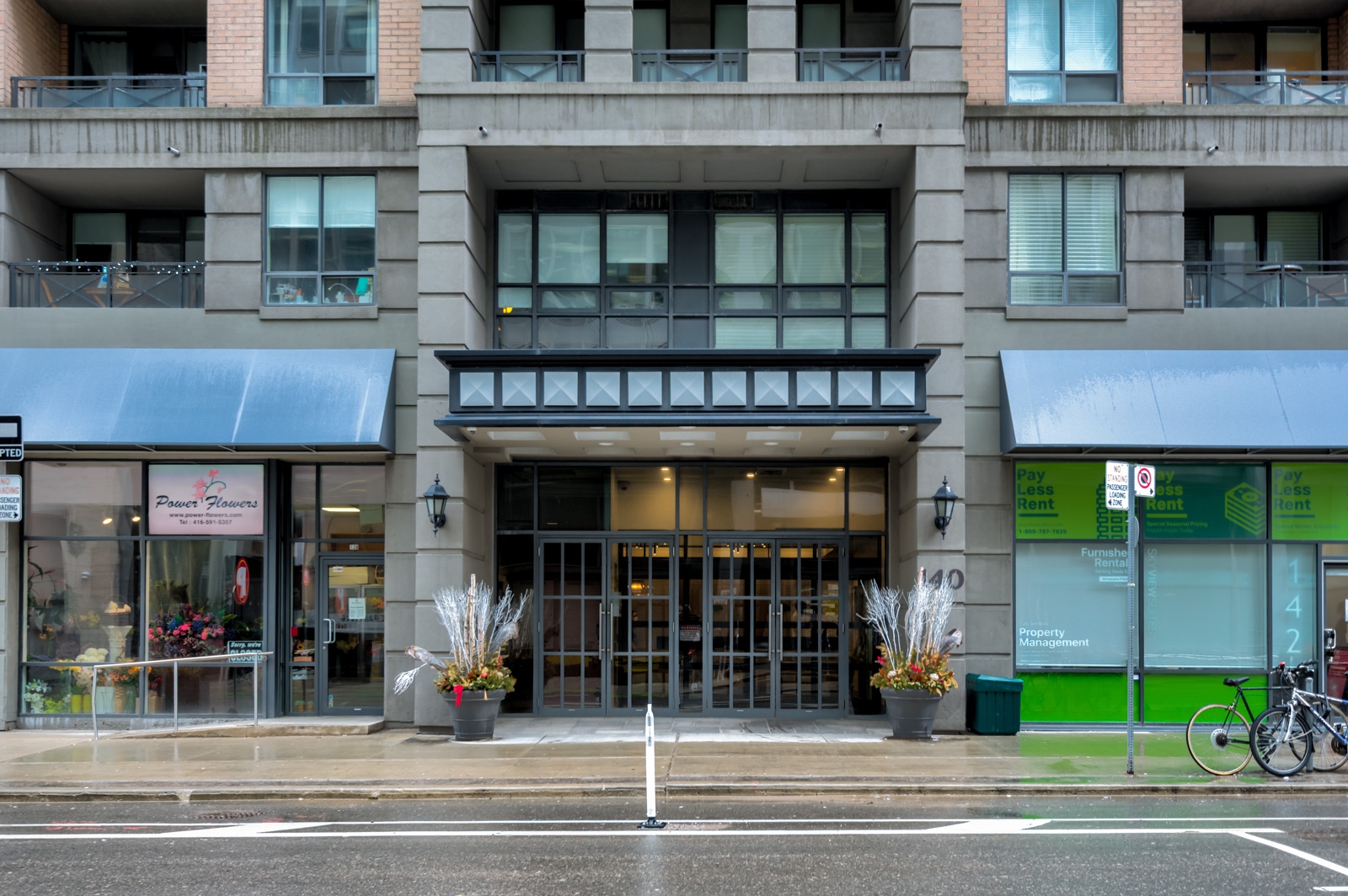 Entrance of 140 Simcoe St with gray stone, pink brick and blue awnings.