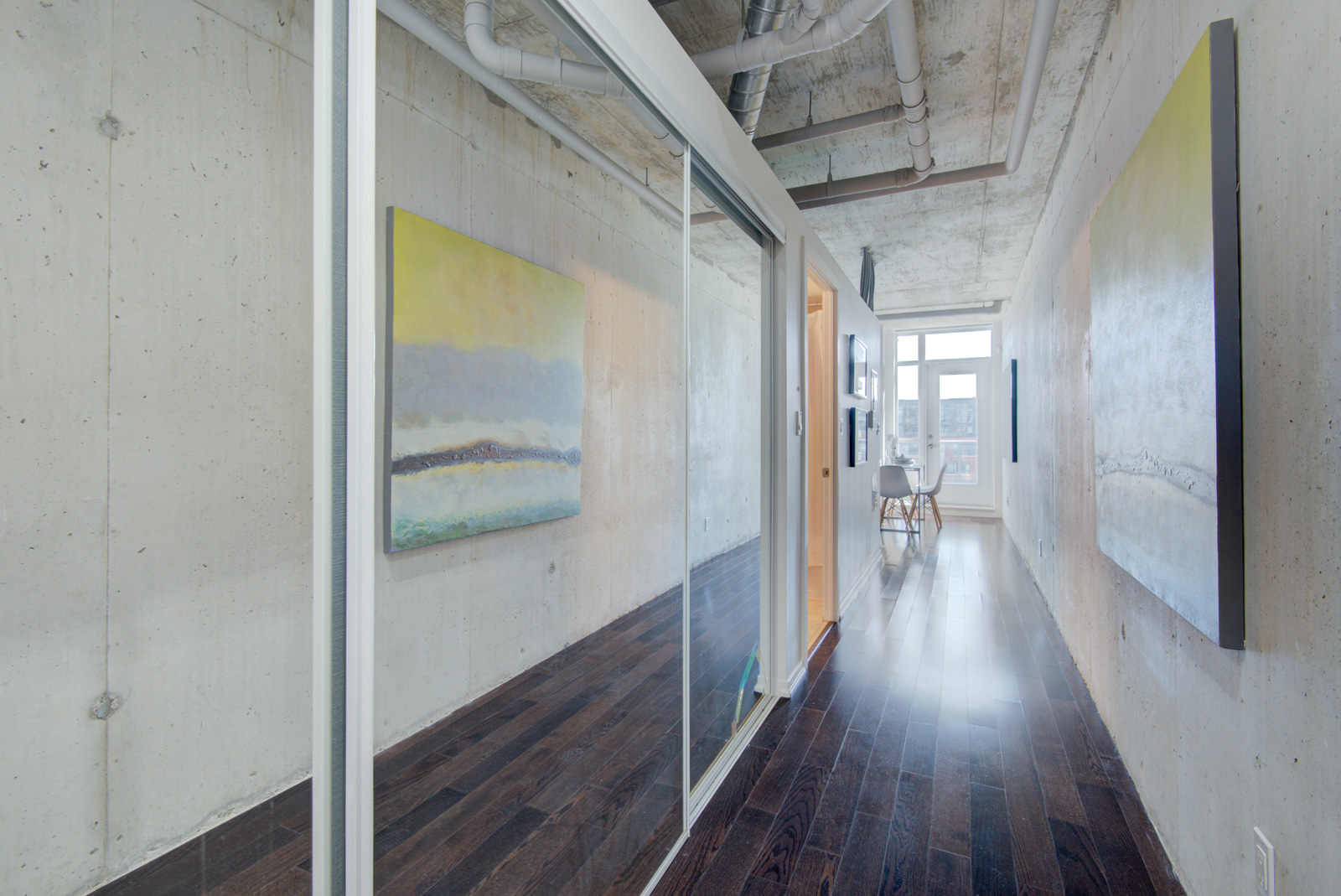 Condo hallway with mirror-door closet and exposed walls.