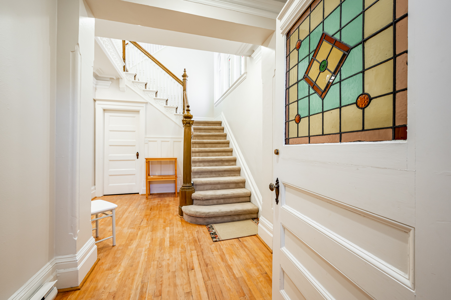 98 Bedford Rd foyer with hardwood floors, carpeted stairs and front door with stained glass inserts.