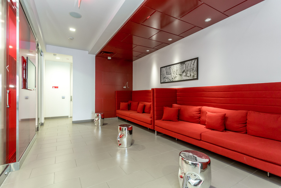 Reve Condos lounge with vibrant red seats and silver tables.
