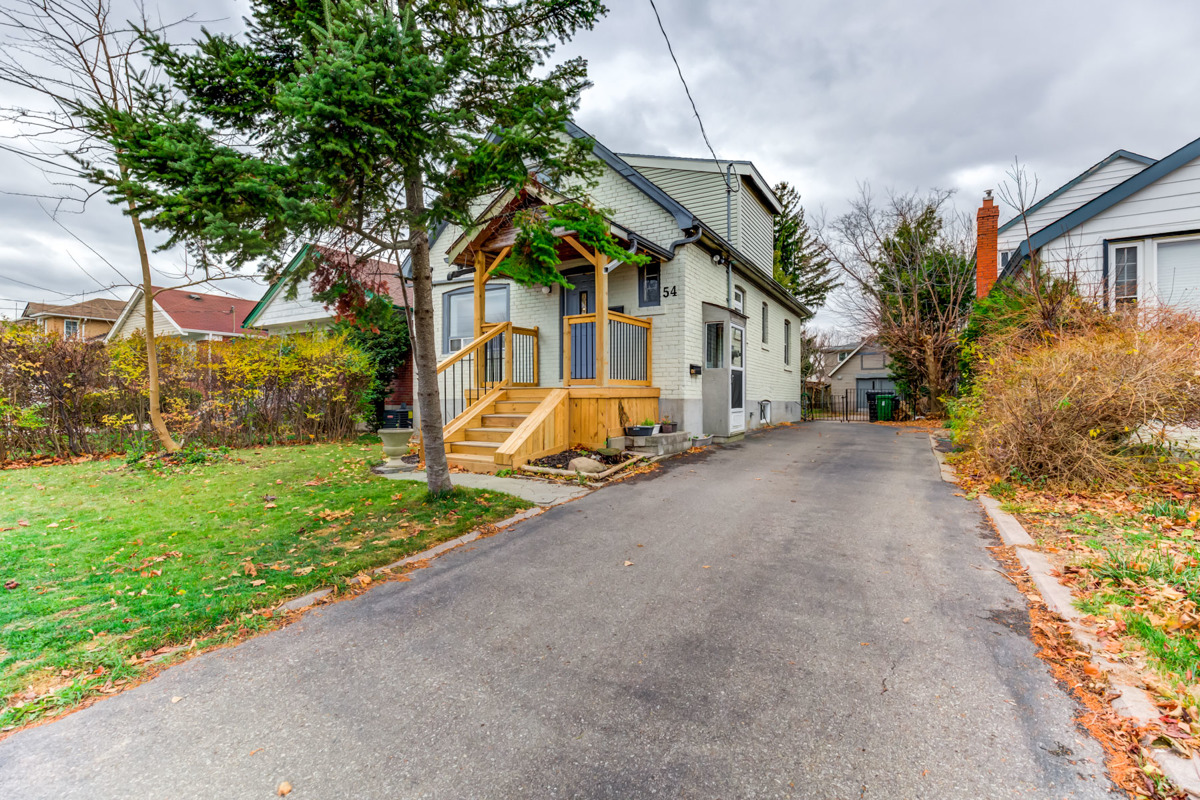 house with large driveway and tree in front yard.