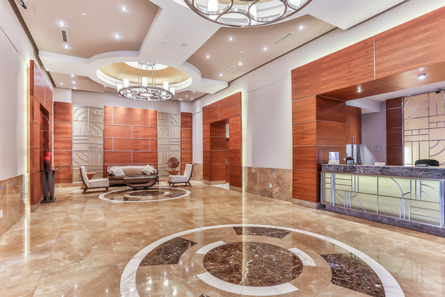 Sophisticated condo lobby with chandeliers, sleek tiles and wall designs.