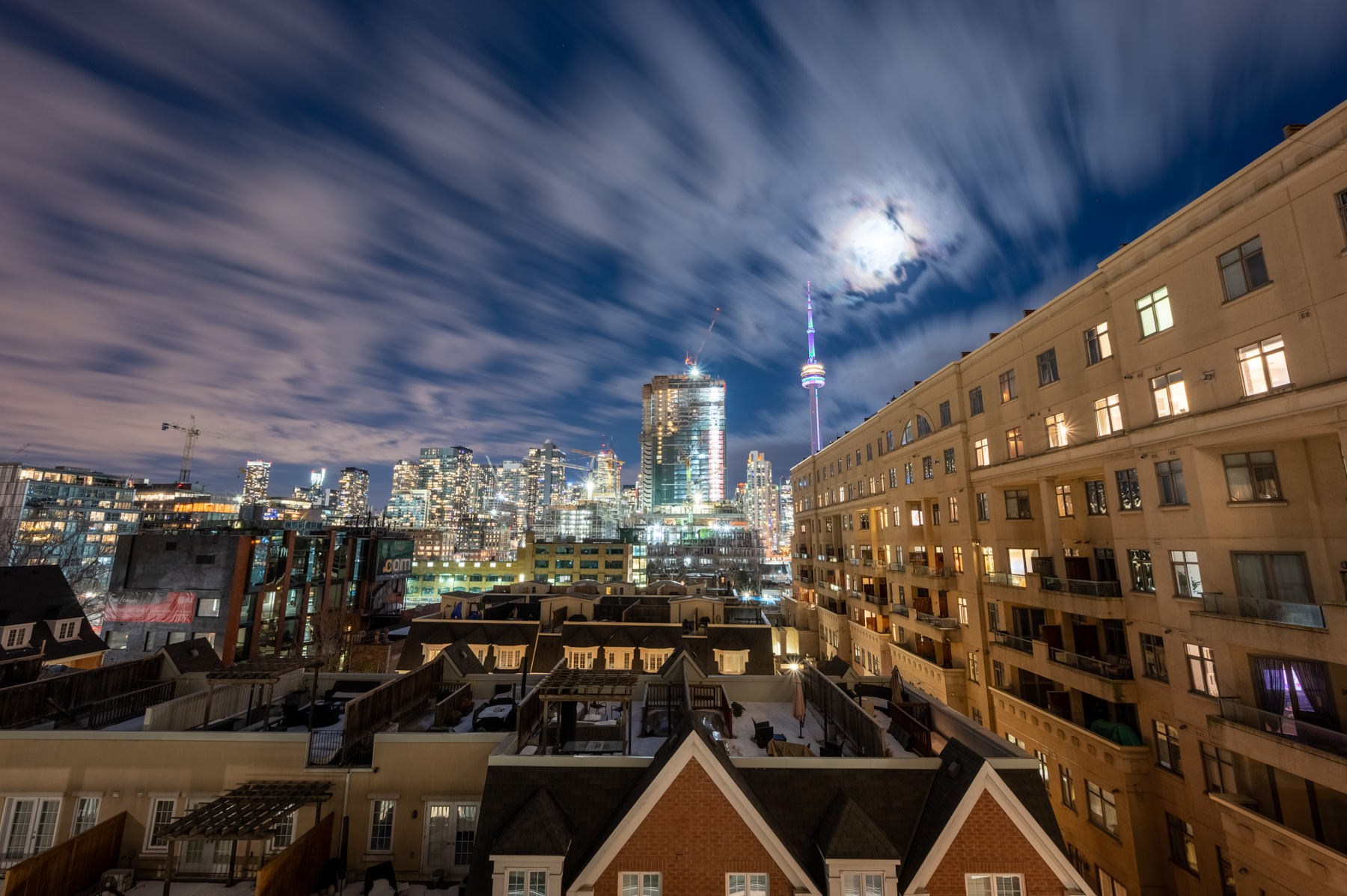 City lights, moonlit skies and blue lights of CN Tower in distance.