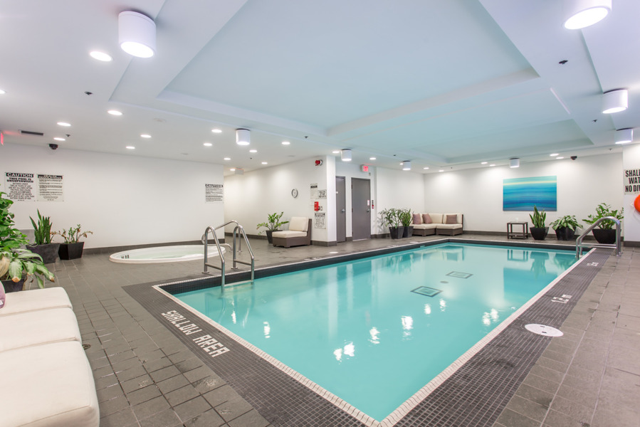 Empty condo swimming pool with greenish water.