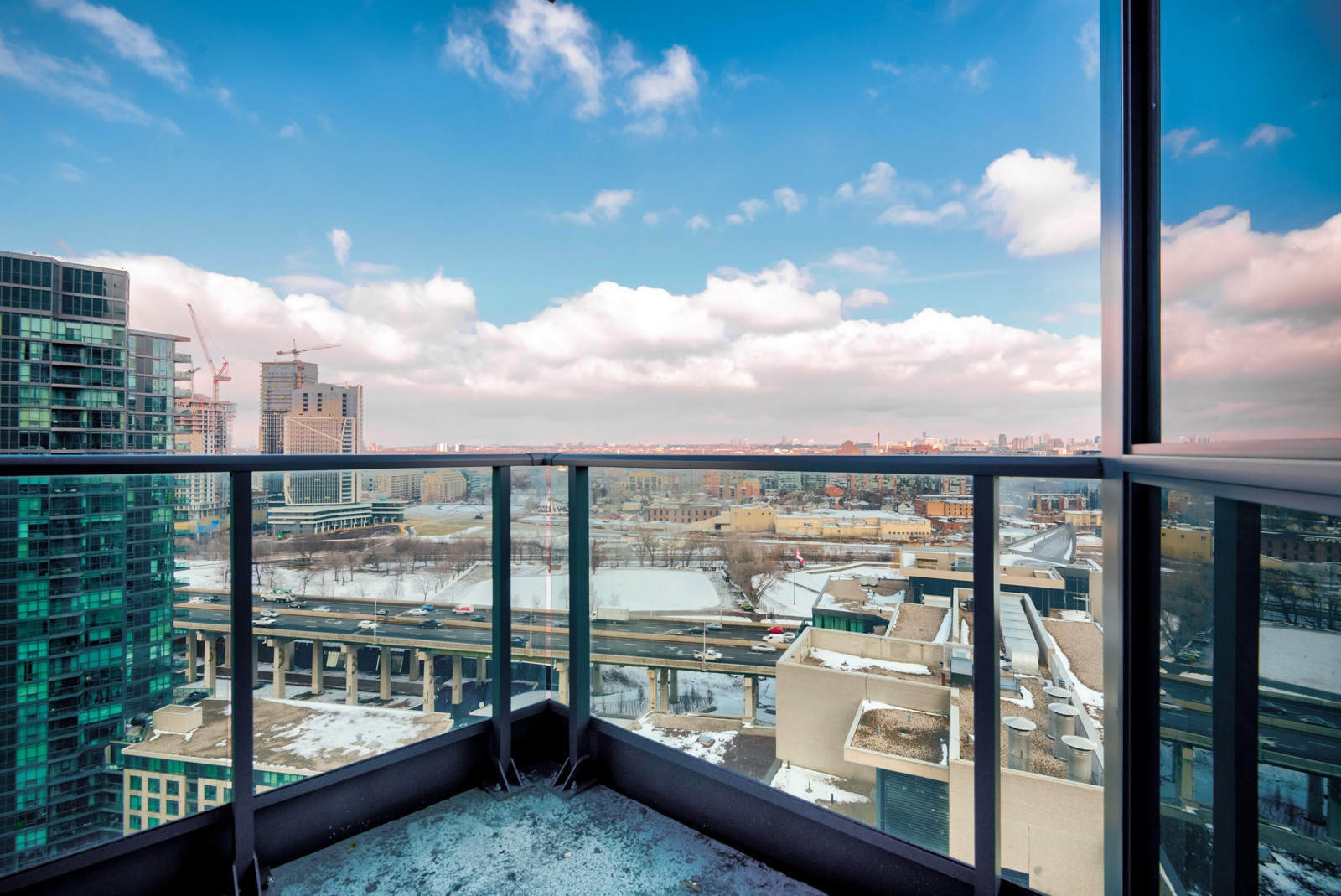 Balcony with black rails and clear glass panels showing Fort York,Toronto.