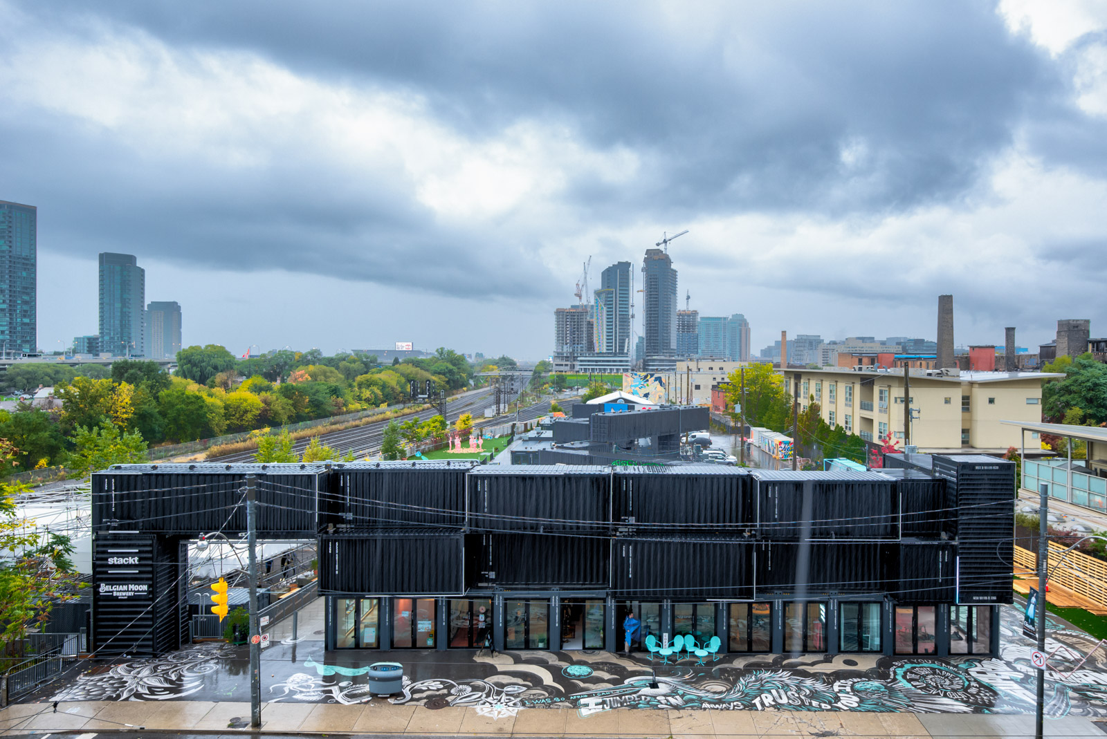 stackt market across Minto Condos with black shipping containers stacked on top of each other and pavement graffiti.