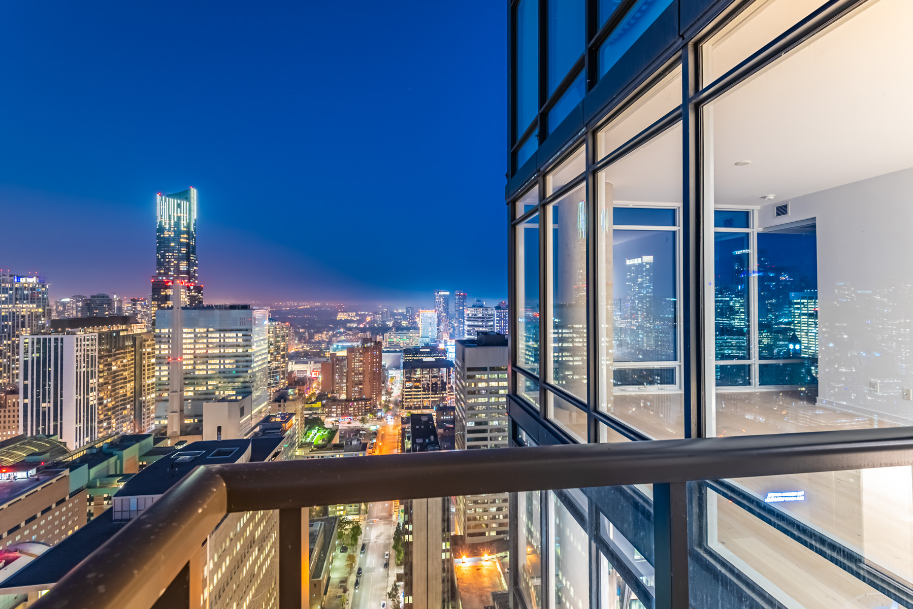 Night view of brightly lit Toronto skyline from 488 University Ave balcony.