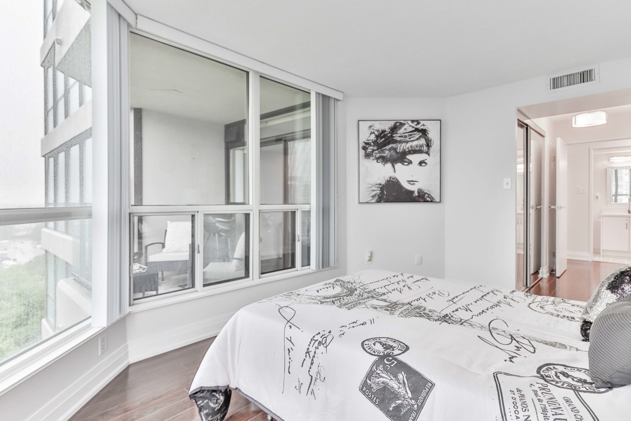 Brightly-lit bedroom showing South Etobicoke through windows.