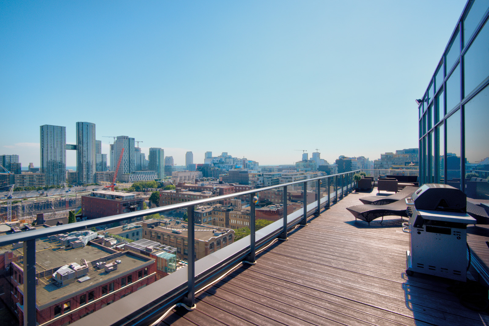 BBQ and lounge chairs with view of Toronto from terrace of Victory Lofts Penthouse Suite in 478 King St W Toronto.