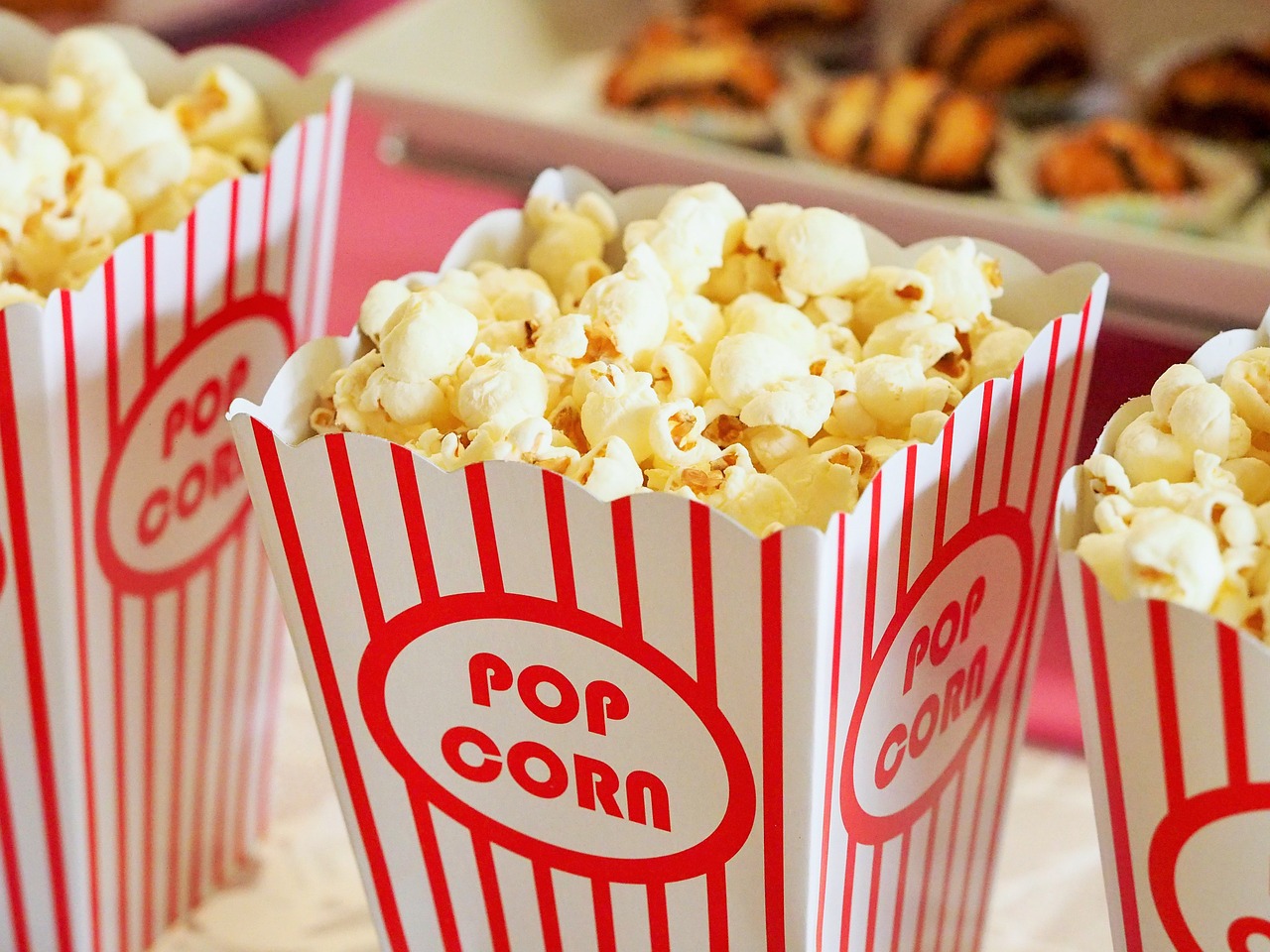 Close up of 3 striped red and white popcorn containers with popcorn.