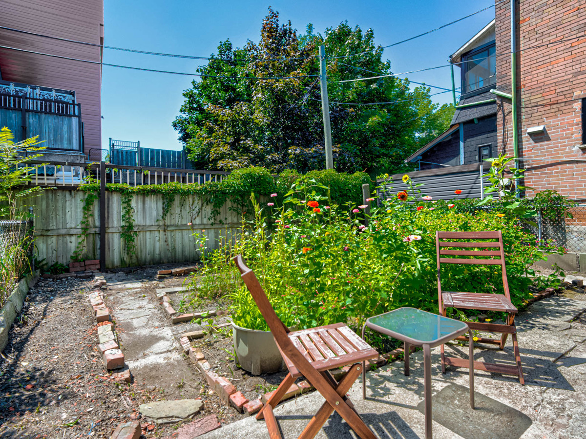 Small fenced garden with flowers and patio furniture.