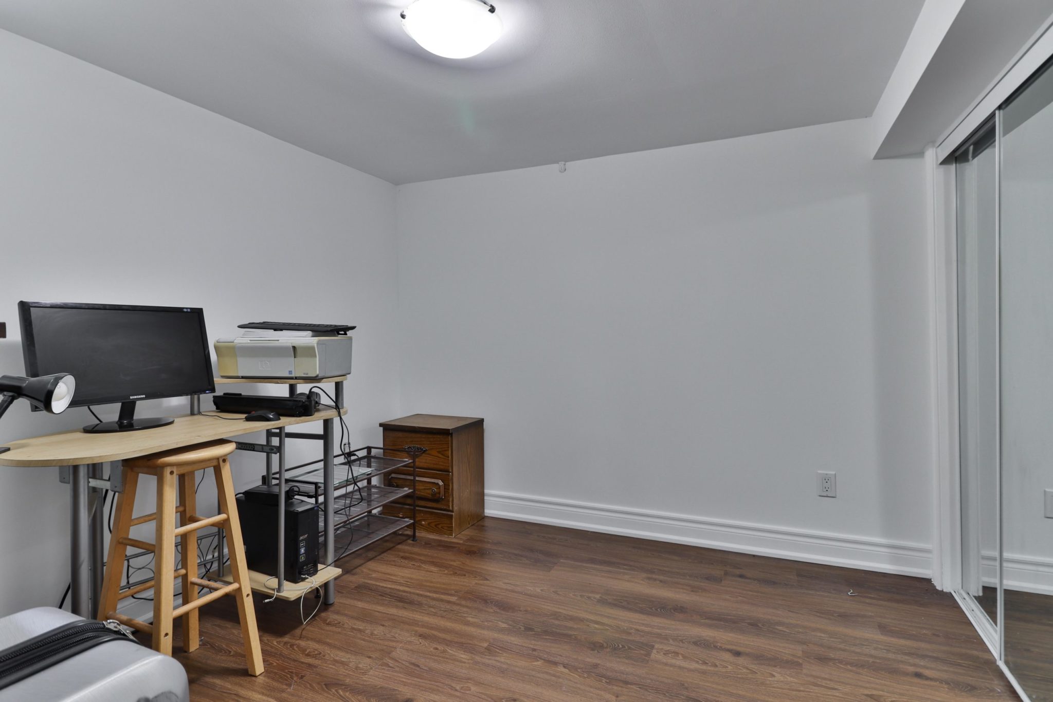 Basement bedroom being used as home office with computer, desk and chair.