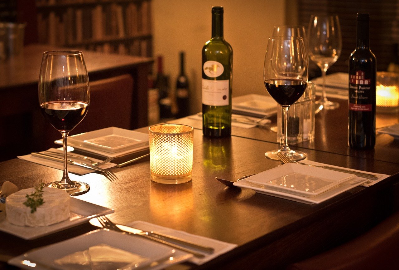 Dimly lit bistro with table, chairs, wine glasses and candles. 