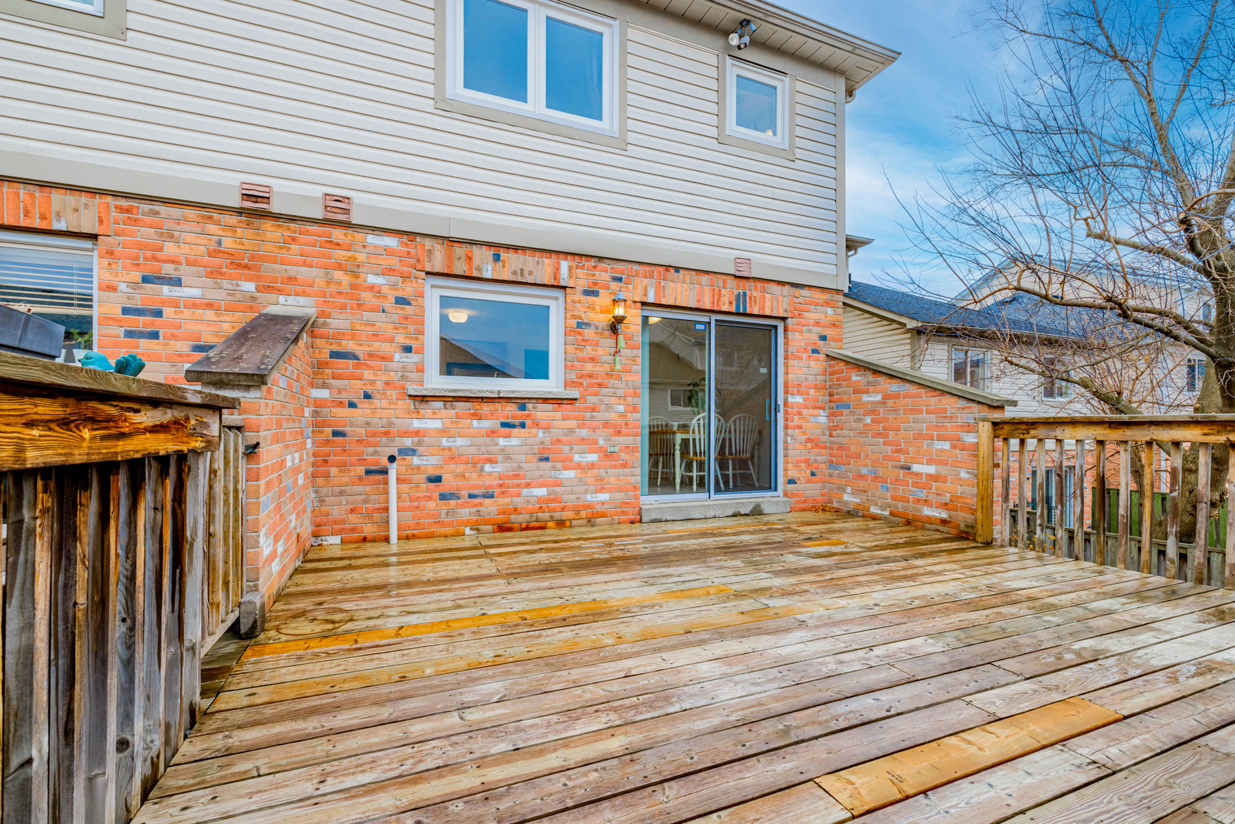 Wooden deck with red-brick wall and wood rails.