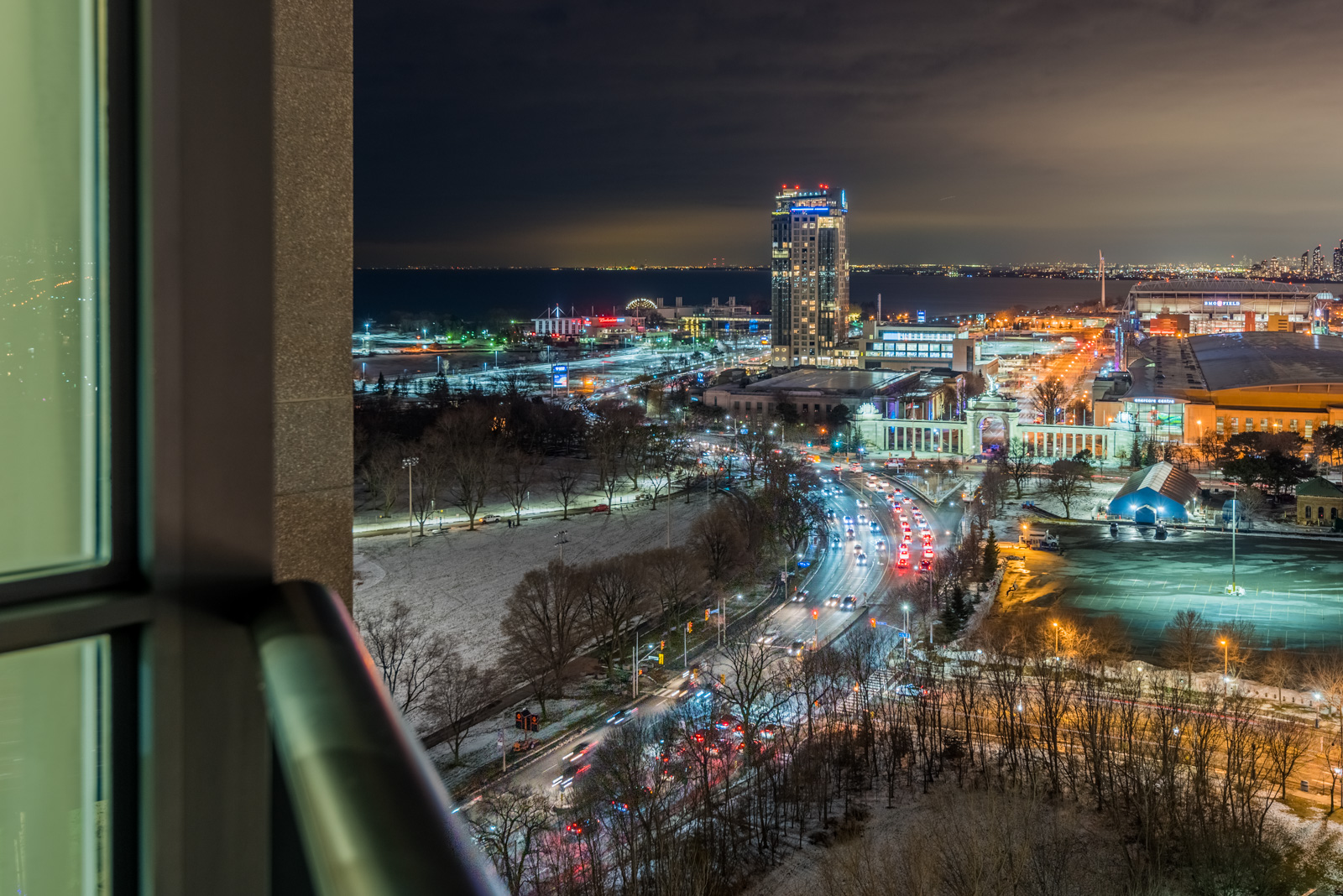 Nighttime view of Lake Ontario, buildings and traffic with glittering red and blue lights.