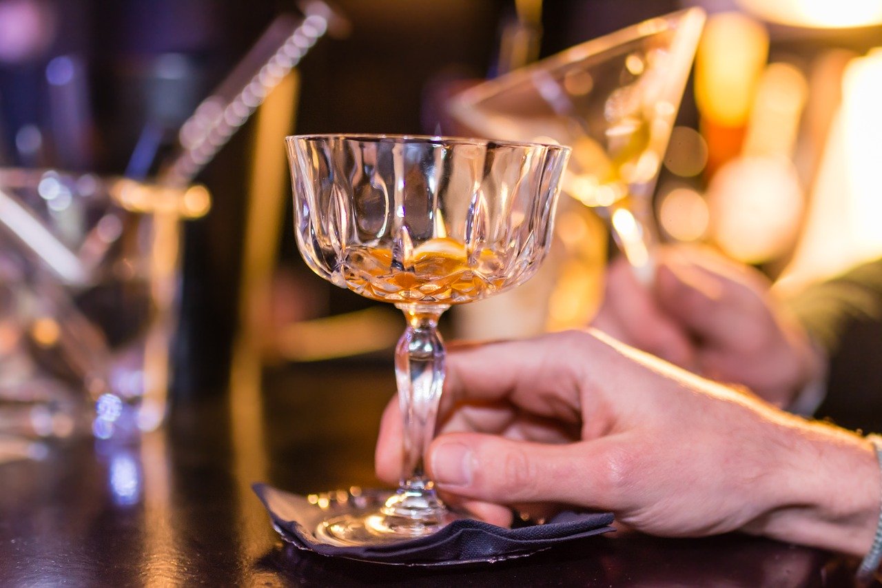 Close up of female hand holding mostly empty glass of alcohol.