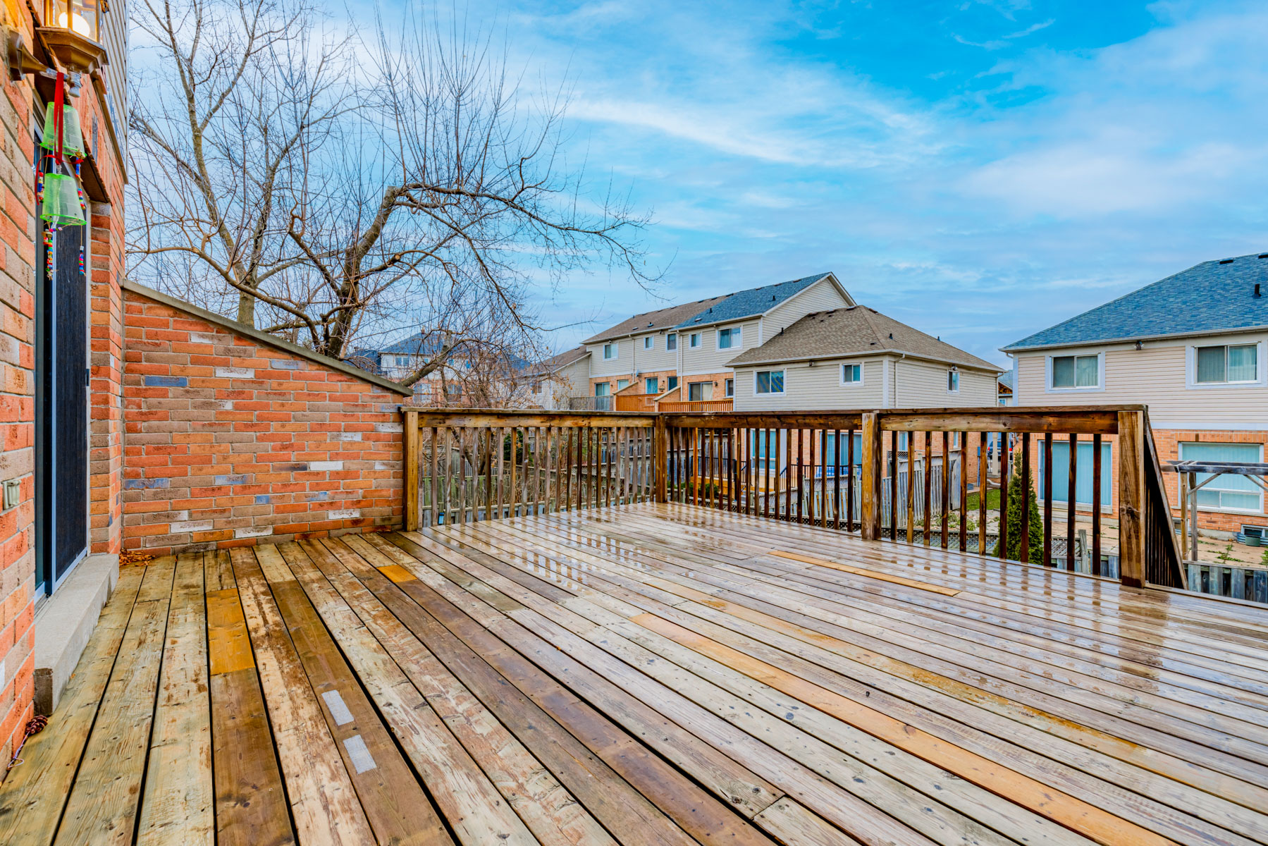 Large wooden deck wet with rain and view of houses.