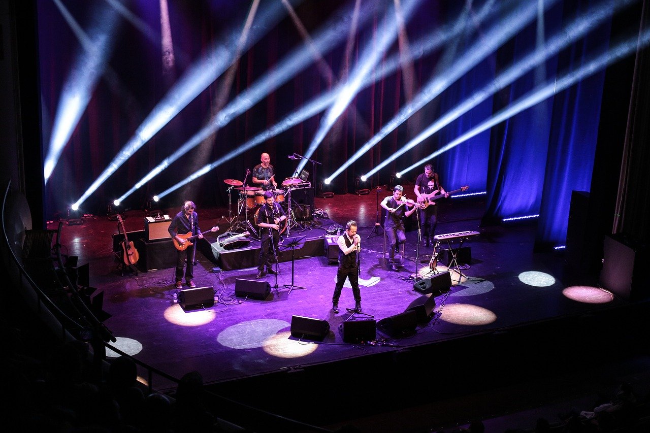 Musicians on stage at a concert with strobe lights.