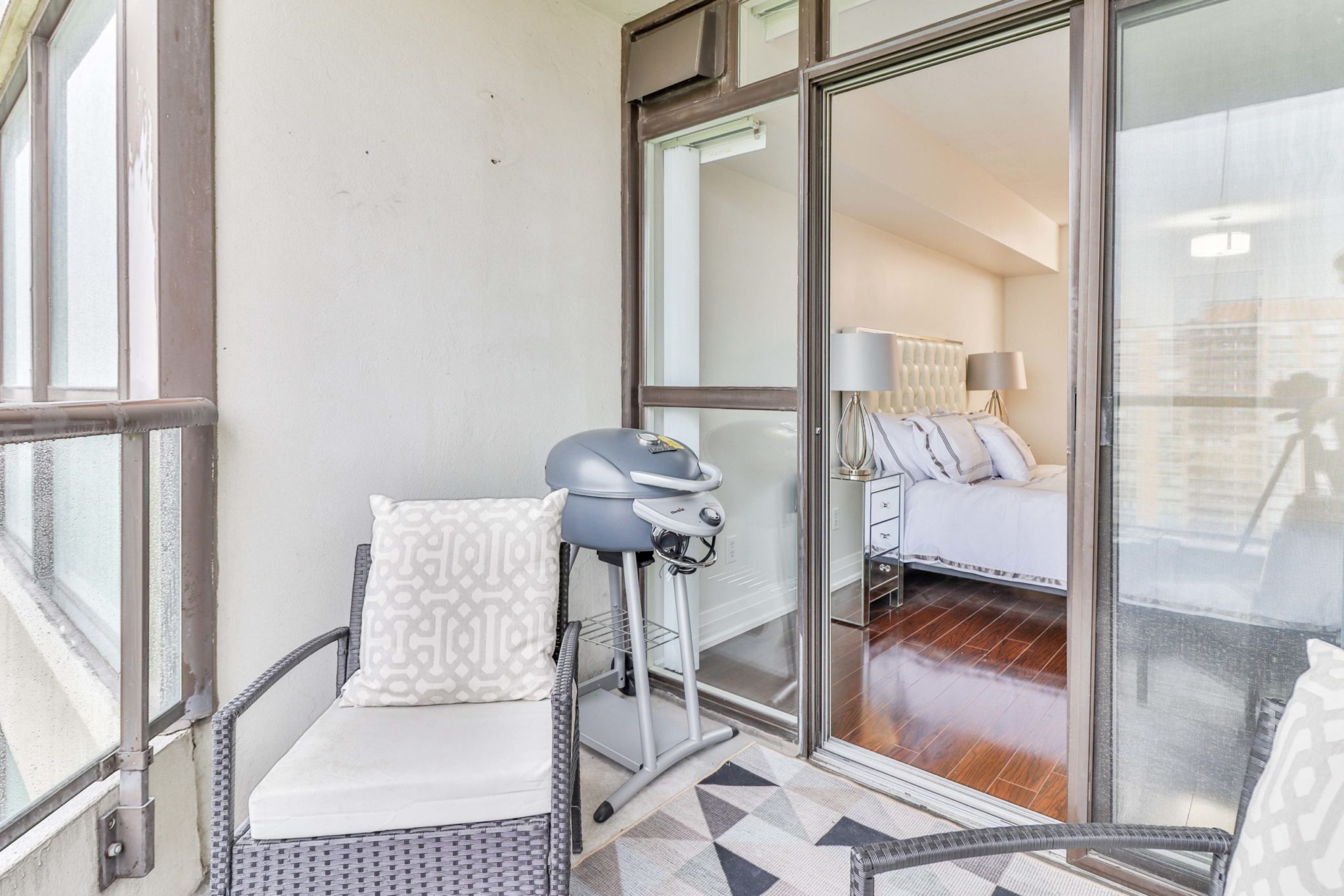 Condo balcony with grill and view of master bedroom in background.