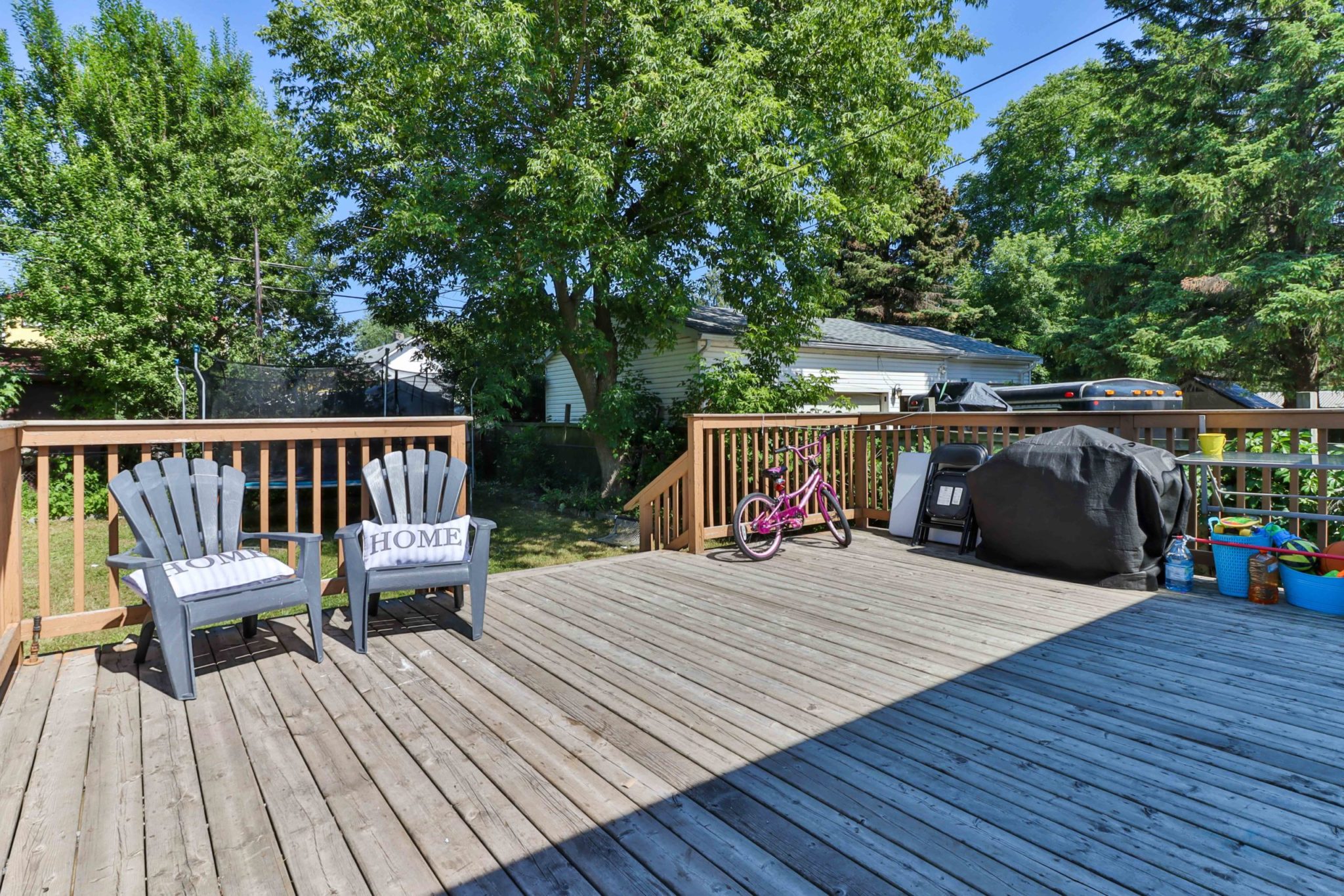 Huge wooden deck with chairs, covered BBQ and bicycle.