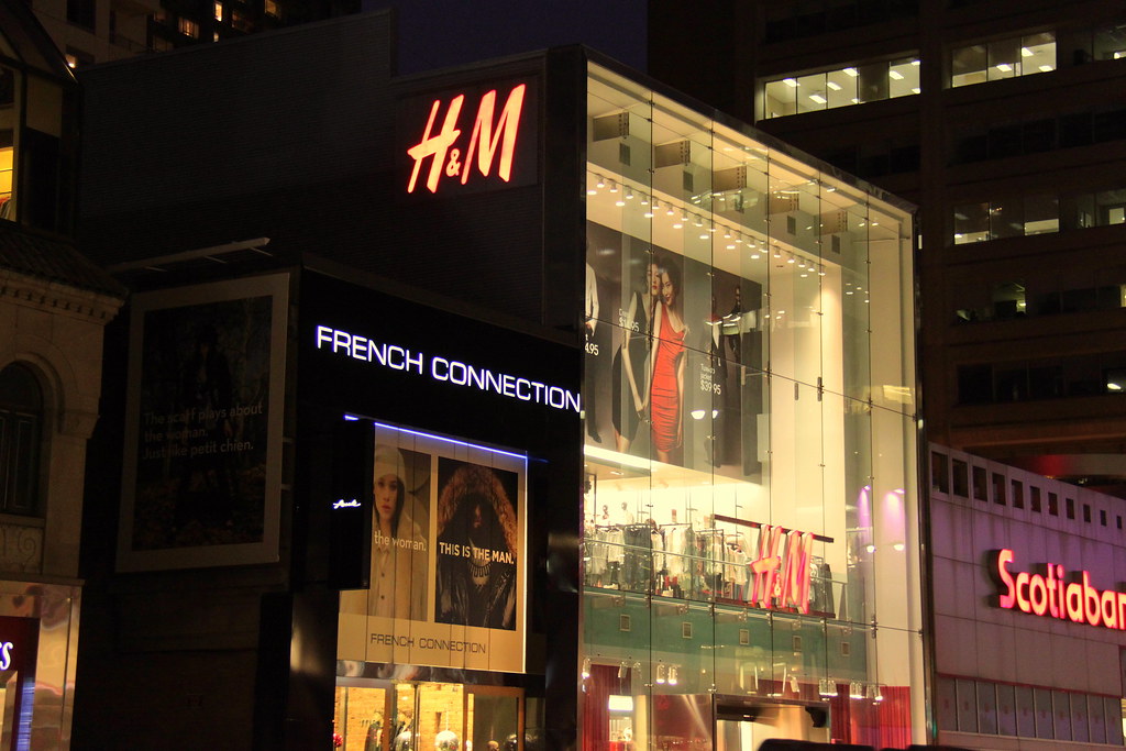 French Connection and H&M storefronts at night in Yorkville, Toronto.
