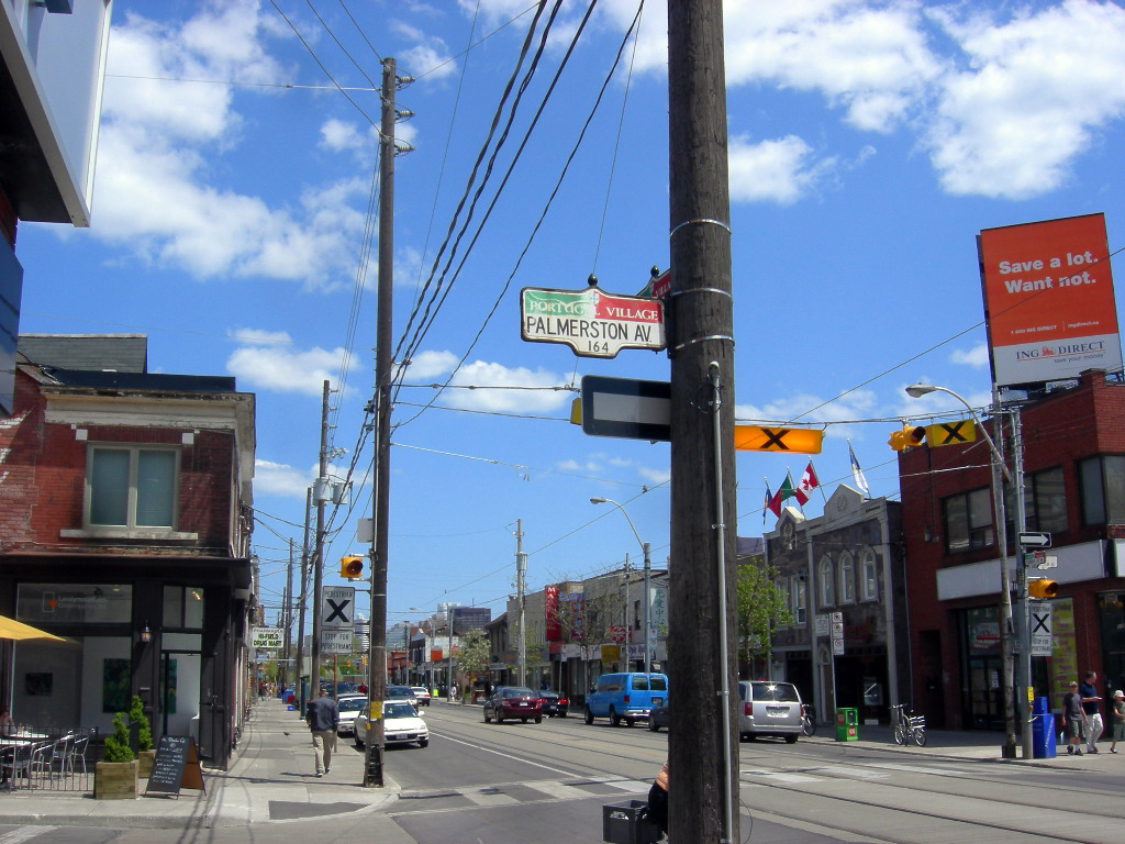 Street signs, pedestrians and cars along Little Portugal, Toronto.