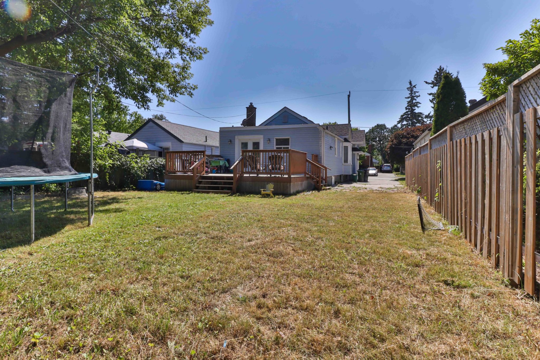 Large backyard with brown grass and wooden fence.