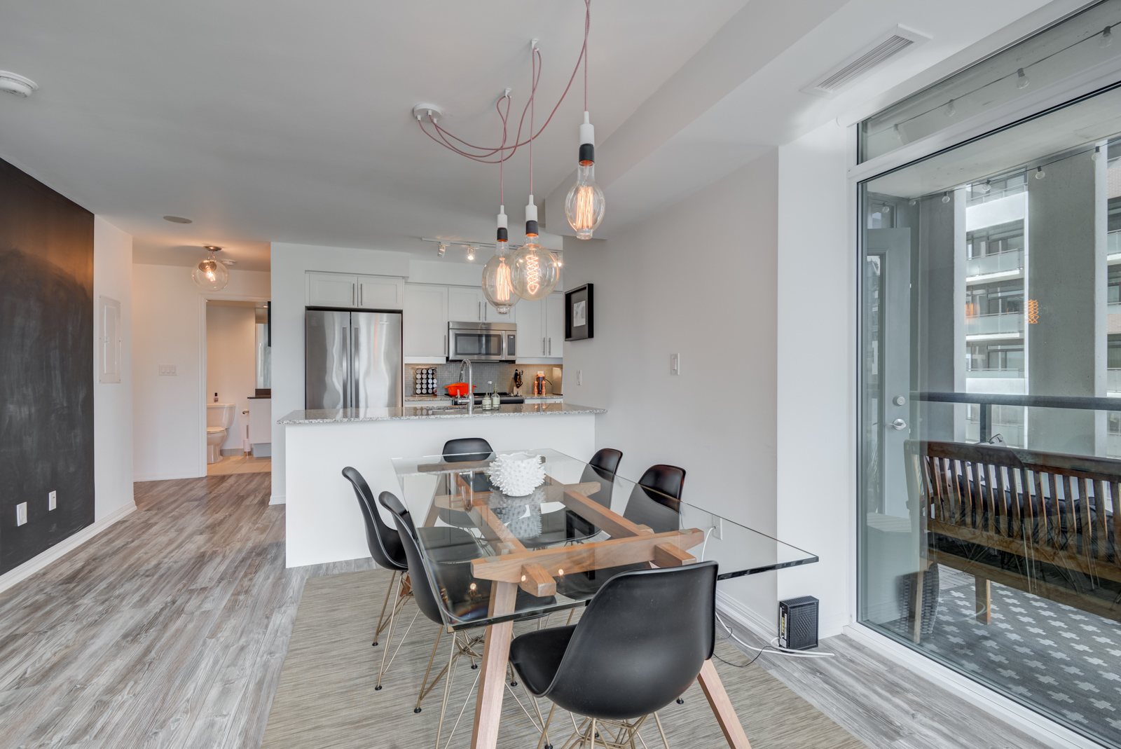 Transparent dining room table with industrial lighting and view of kitchen.