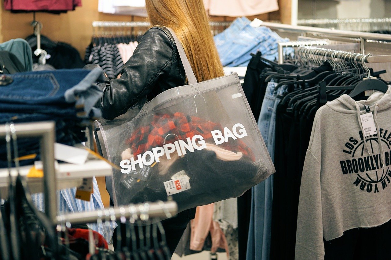 Young woman shopping among clothes racks.