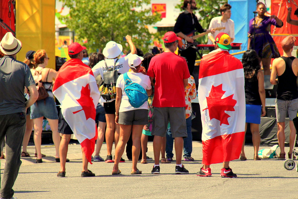 People wrapped in Canadian flags watching concert at Canadian National Exhibition.