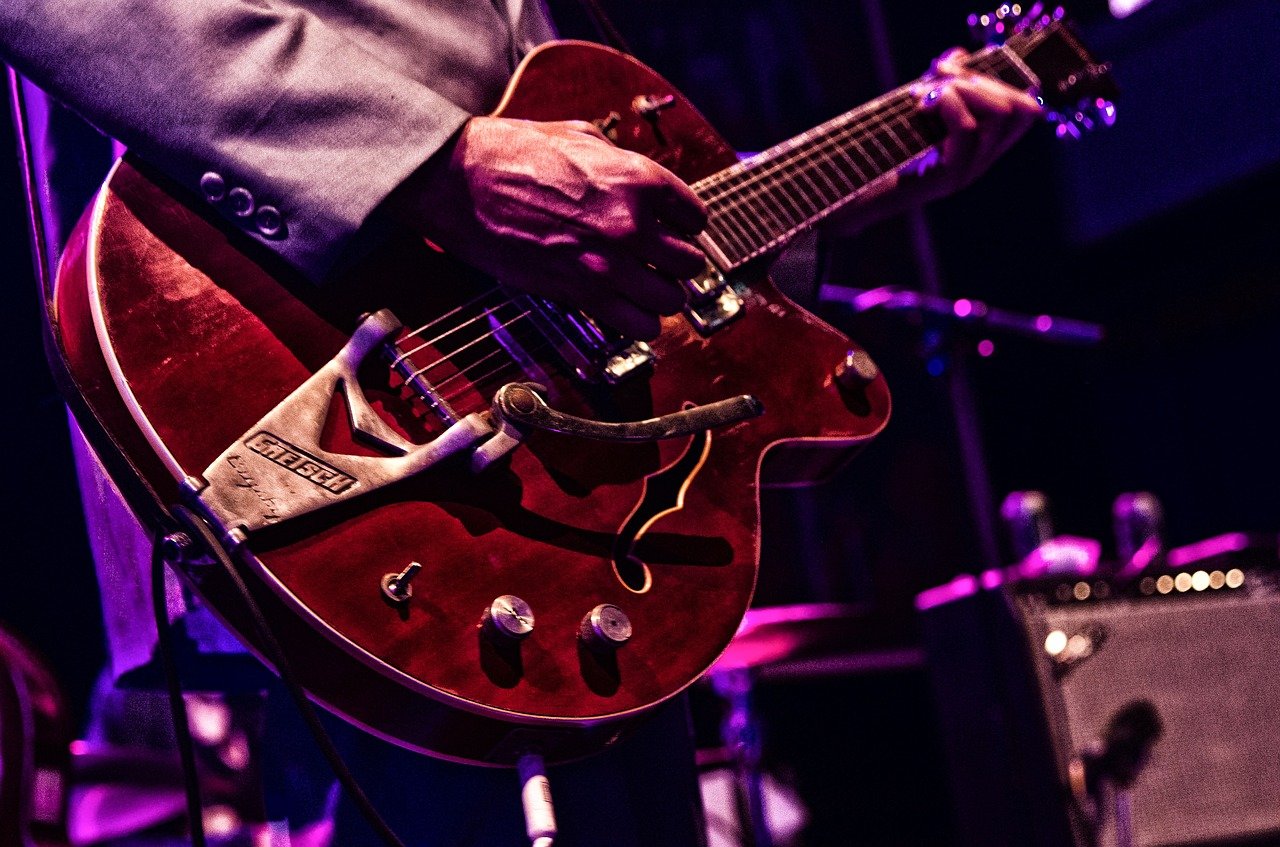 Close up of man holding red guitar.