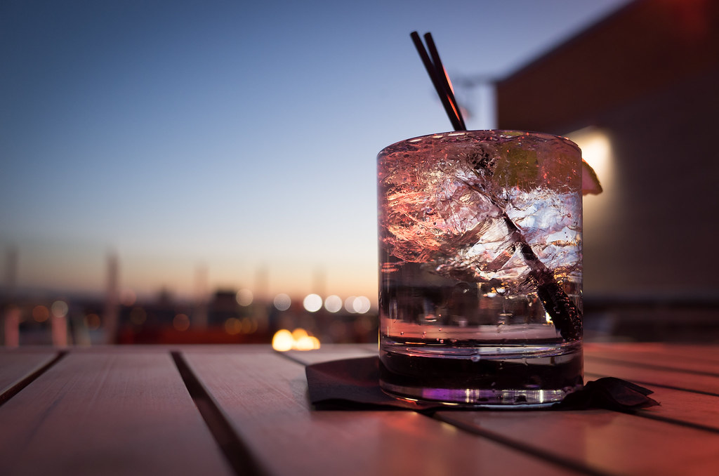 Close up of glass filled with alcohol and ice on patio table. 