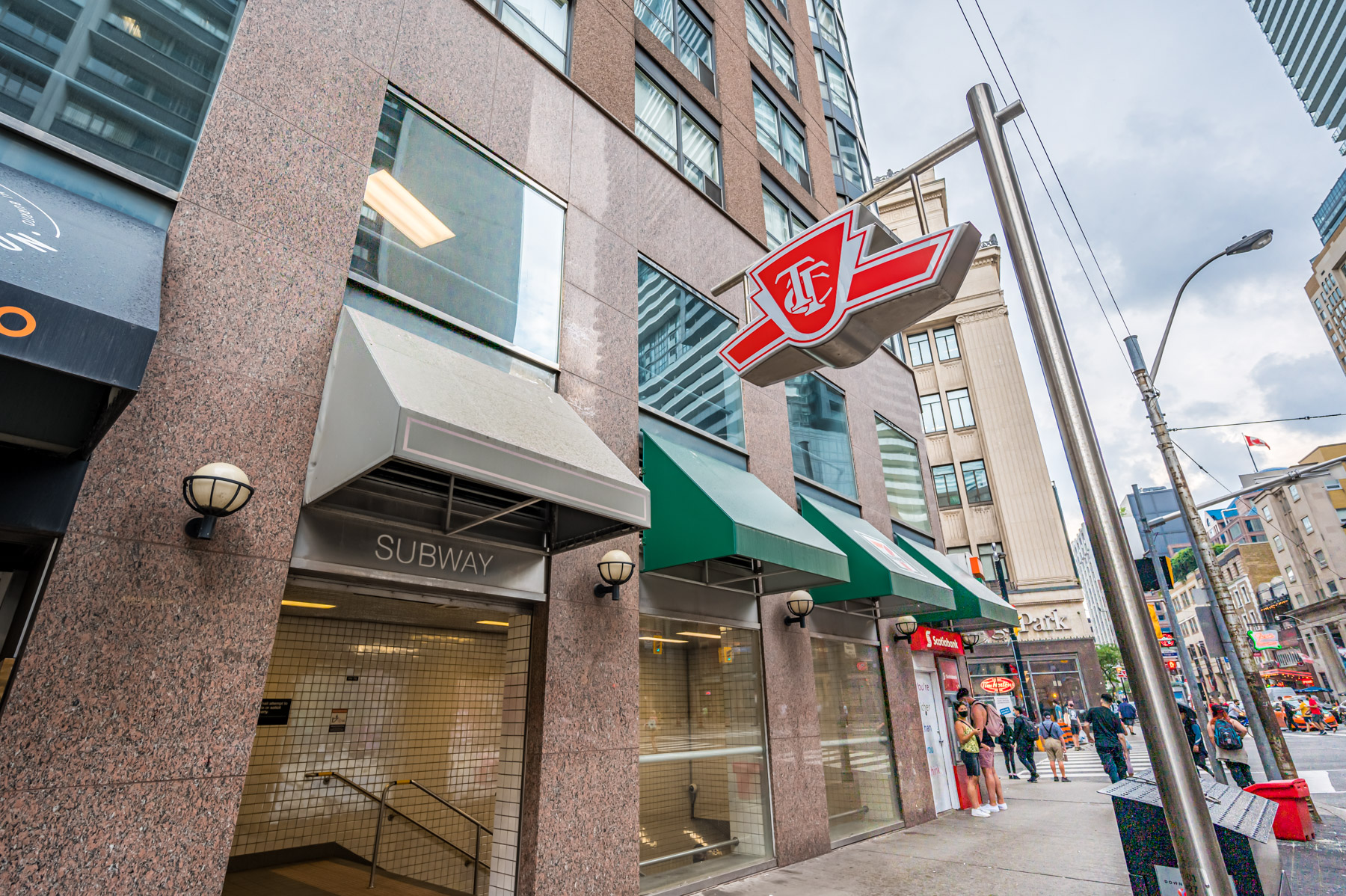 Photo of red TTC subway sign outside College St subway.