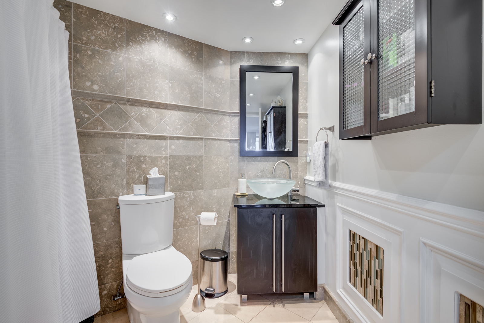 Contemporary bathroom with ceramic tiles, brown vanity, medicine cabinet, and vessel sink bowl of glass.