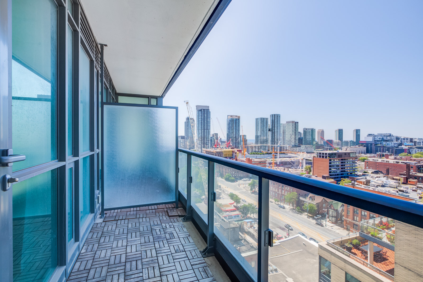 Balcony with glazed divider, glass panels and tiled floors overlooking King West in the Entertainment District.