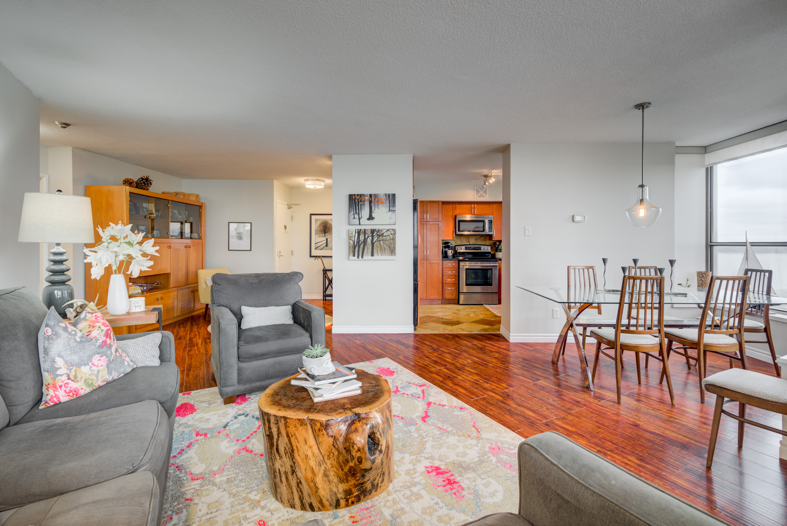 View of living room, dining room, kitchen and den with carpet, gray walls and red laminate floors.