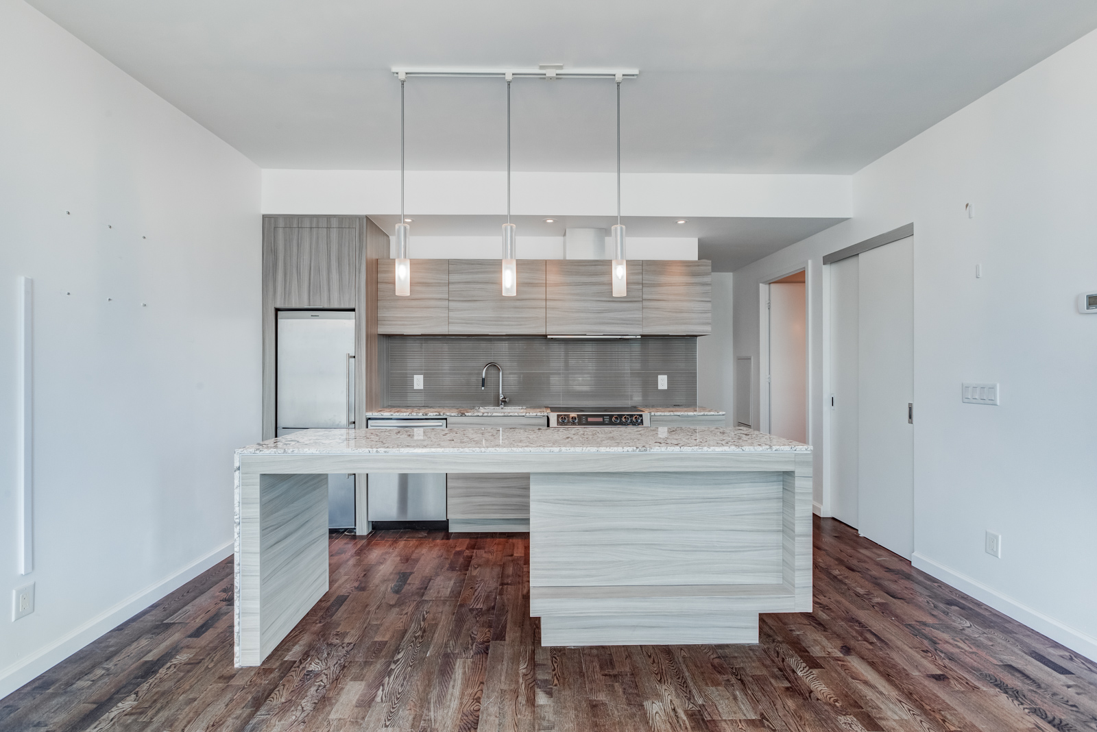 Kitchen breakfast bar with marble top and wooden base along with cabinets and appliances.