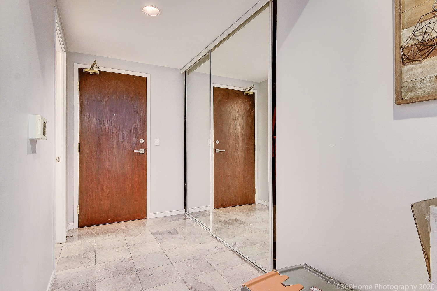 Condo foyer with white marble tiles and double-door closet.