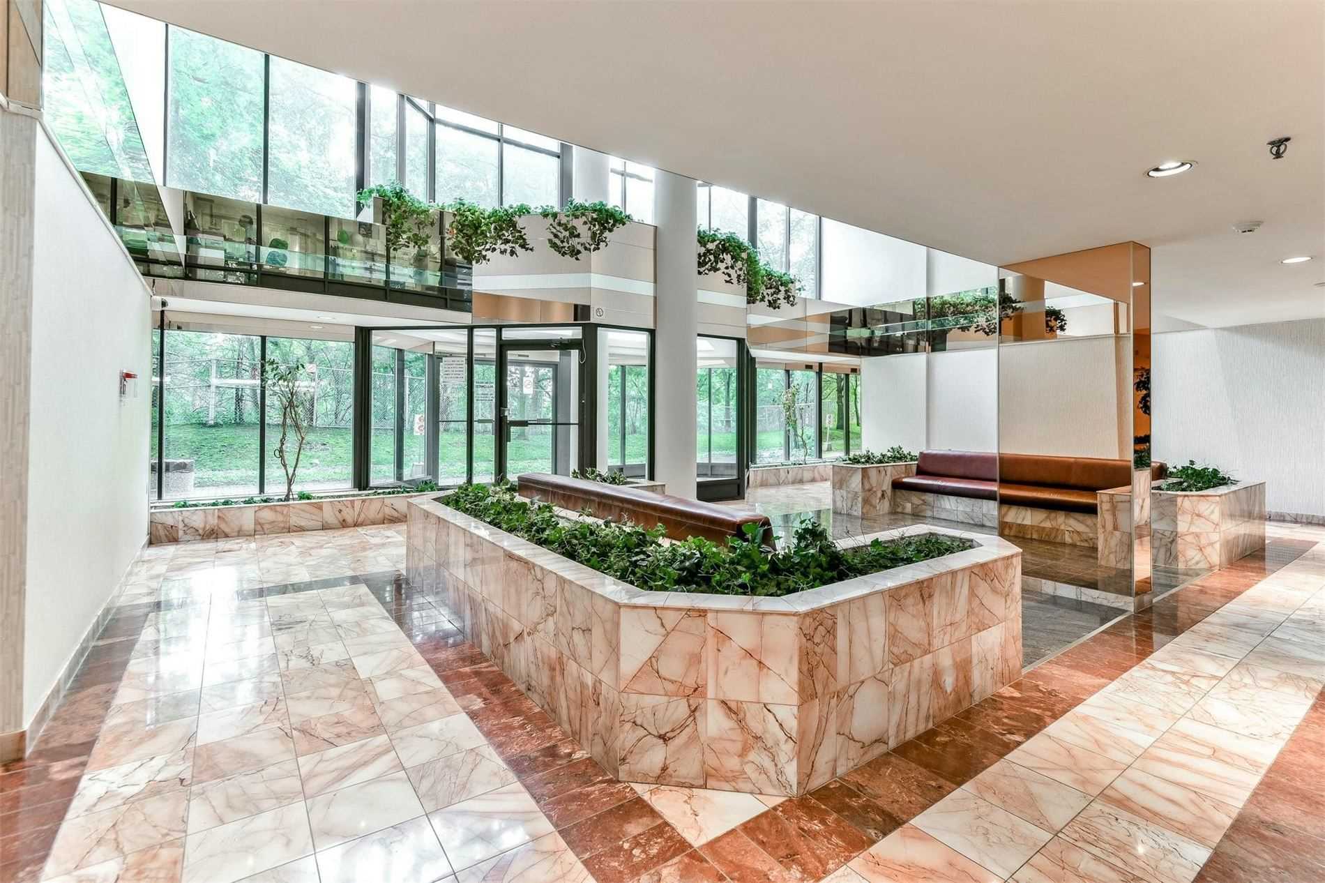 Opulent lobby with light-brown marble tiles and greenery.