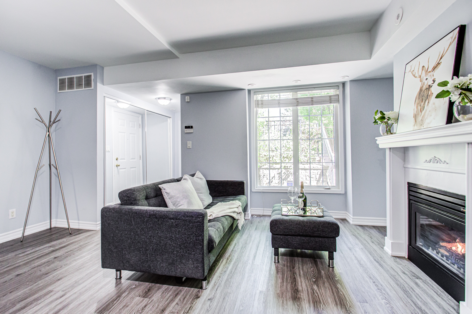 Newly-renovated condo-townhouse living room with dark gray sofa and ottoman.