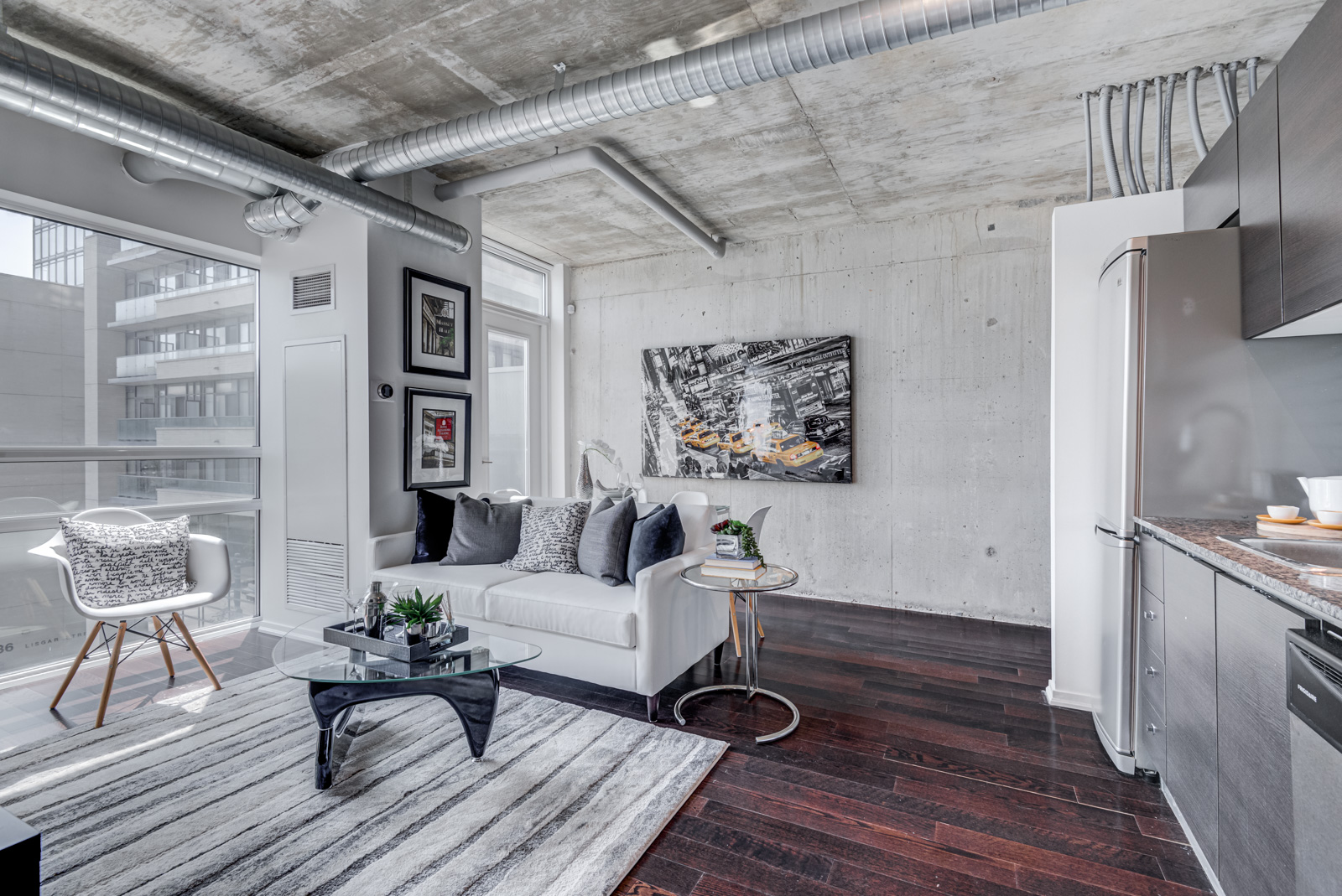 Living and dining room with exposed concrete ceiling, wall, ductwork and piping.