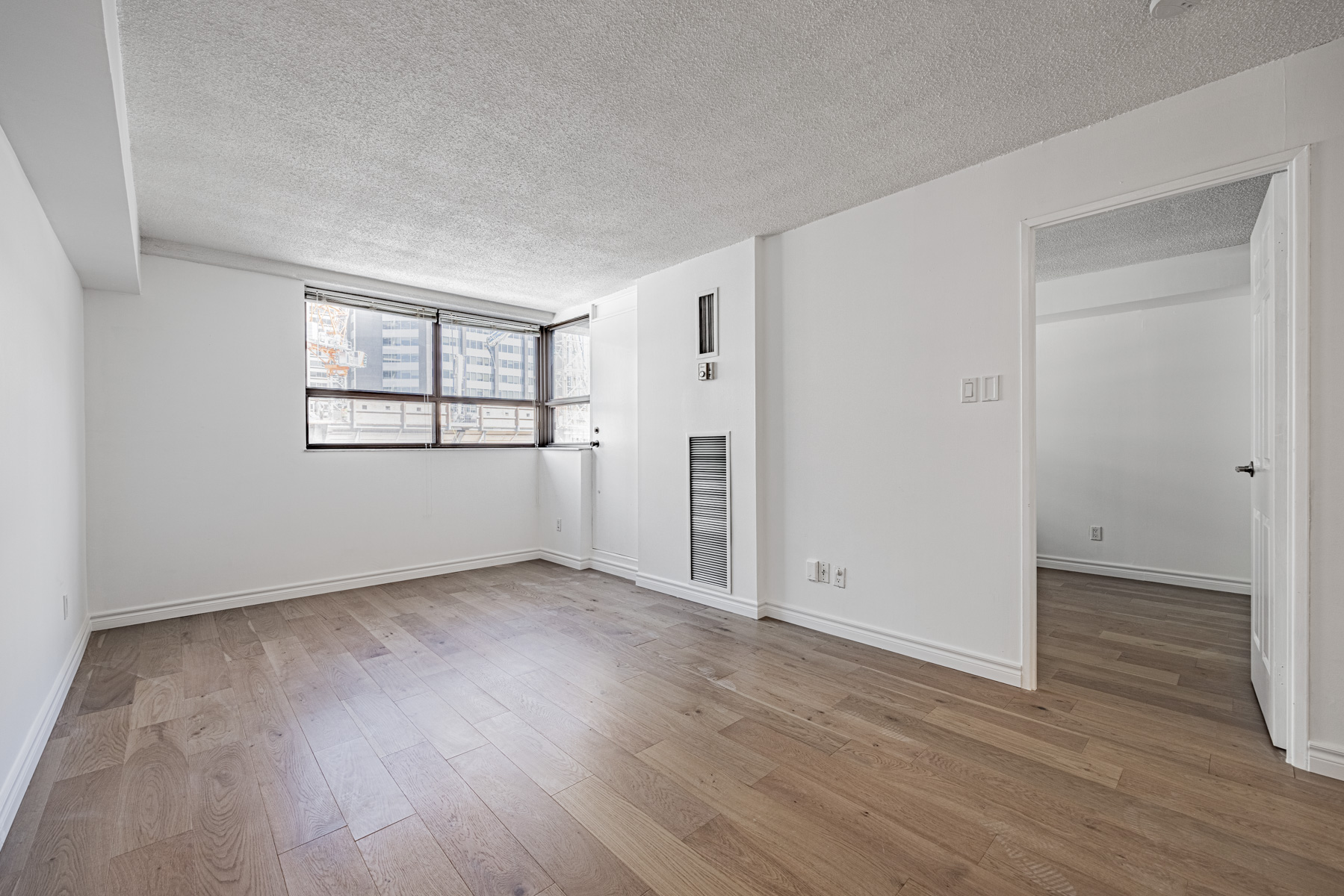 Condo living room with wide-plank hardwood floors.