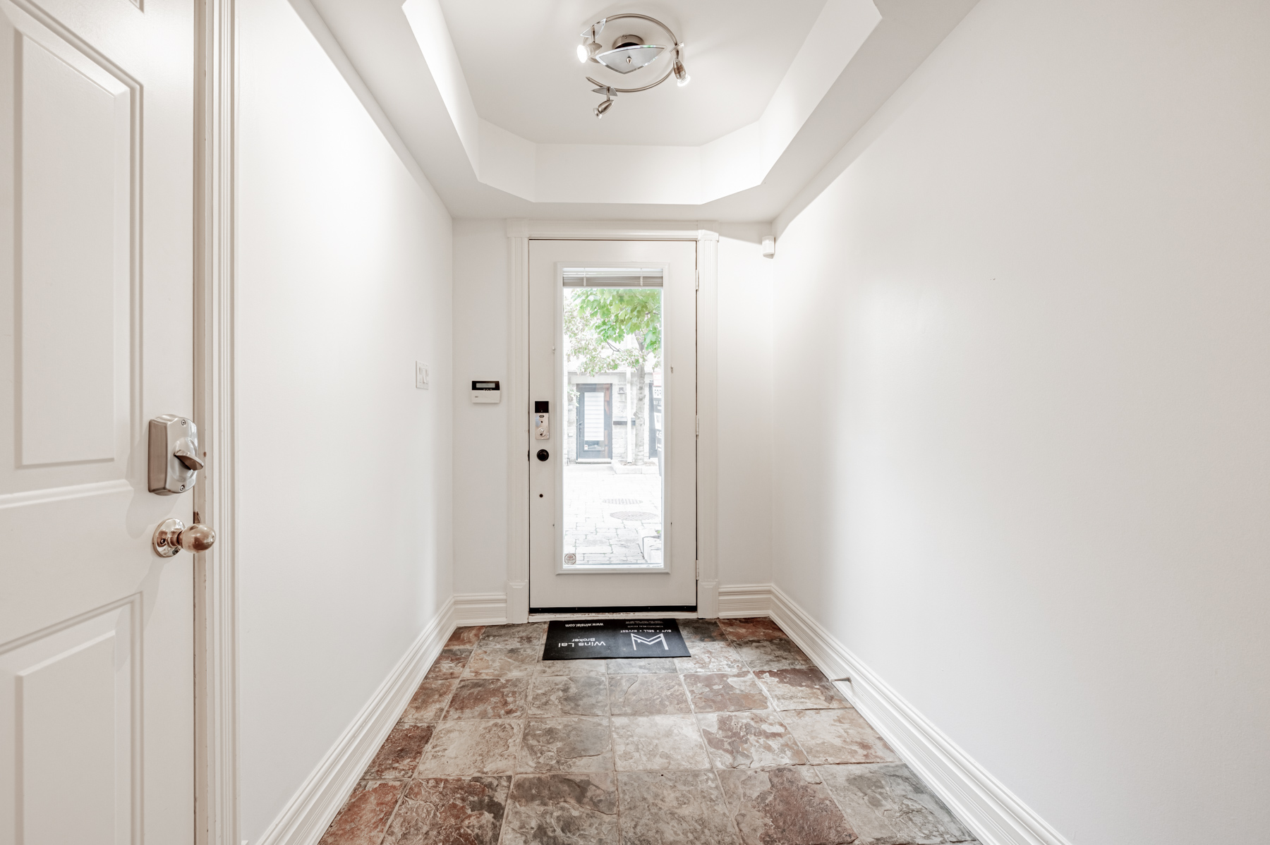 Foyer with reddish stone tiles and modern chandelier – 23 Annex Lane.