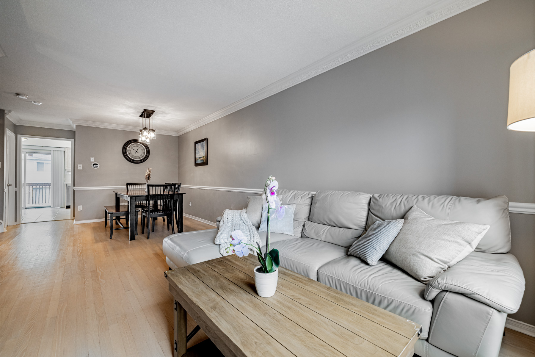 Living and dining room with gray walls, crown moulding and wainscoting.