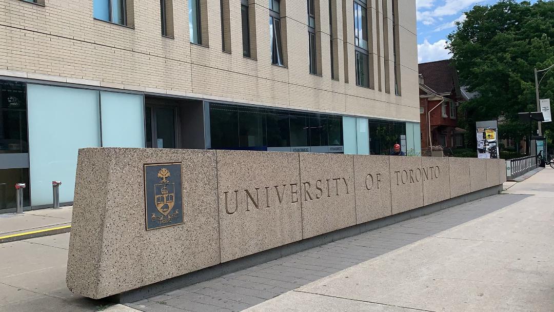 University of Toronto sign and coat of arms etched in stone in Annex neighbourhood near Bathurst.